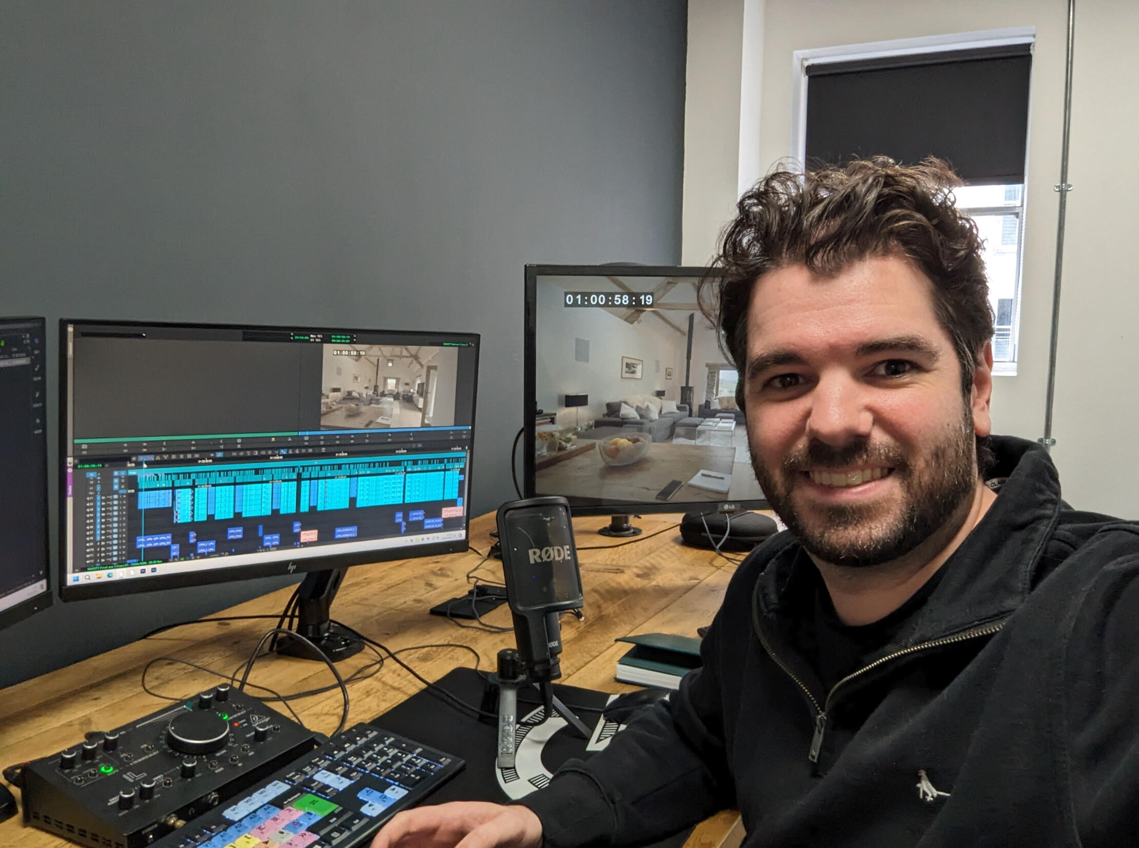 A smiling man working in an editing suite.